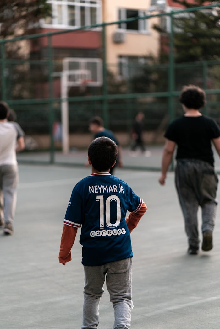 Kids in jerseys playing basketball on an outdoor court in Istanbul, creating a joyful and playful scene.